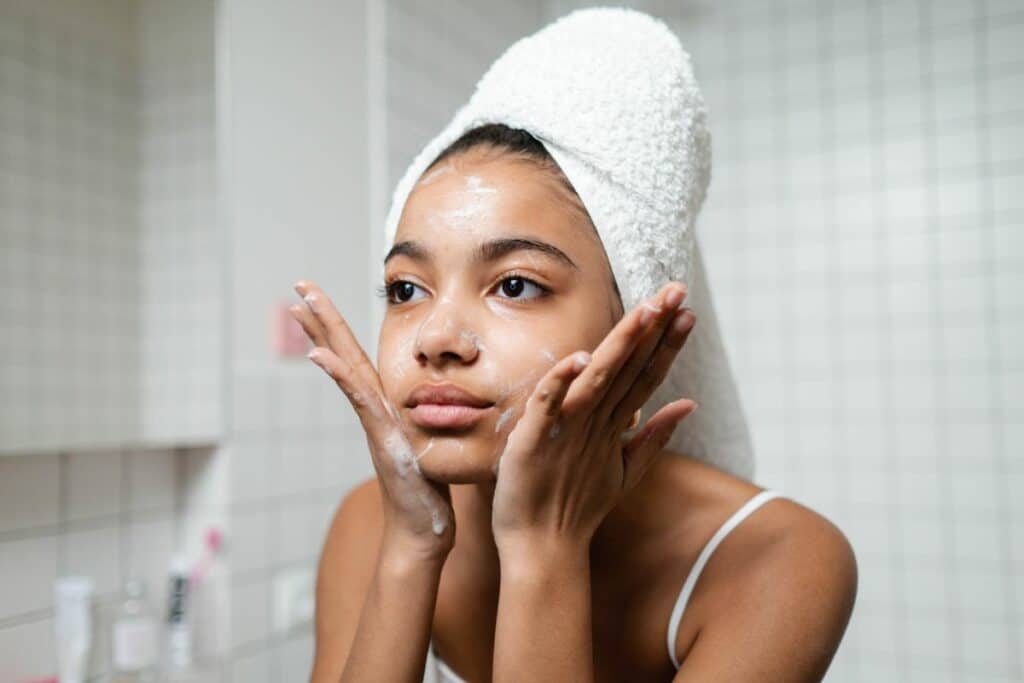 A young woman washing her face, splashing clean water on her skin, embodying a refreshing skincare routine.