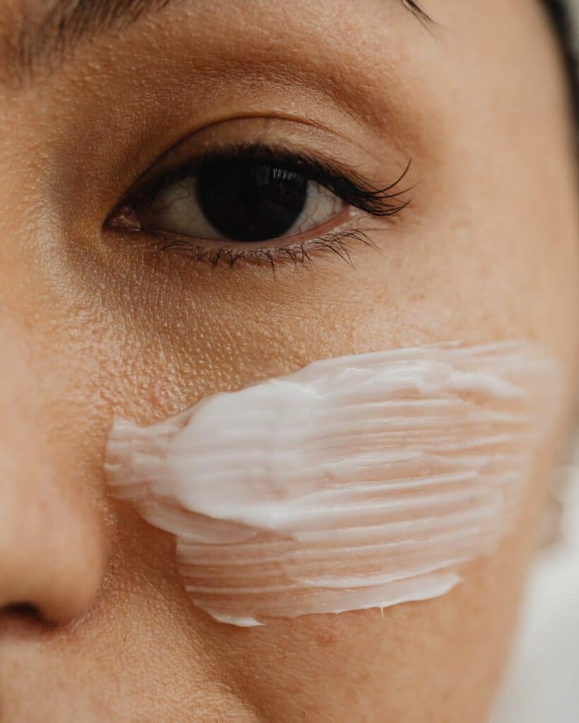 A woman applying face cream, depicting a moment in her daily skincare routine focused on moisturization and skin nourishment.