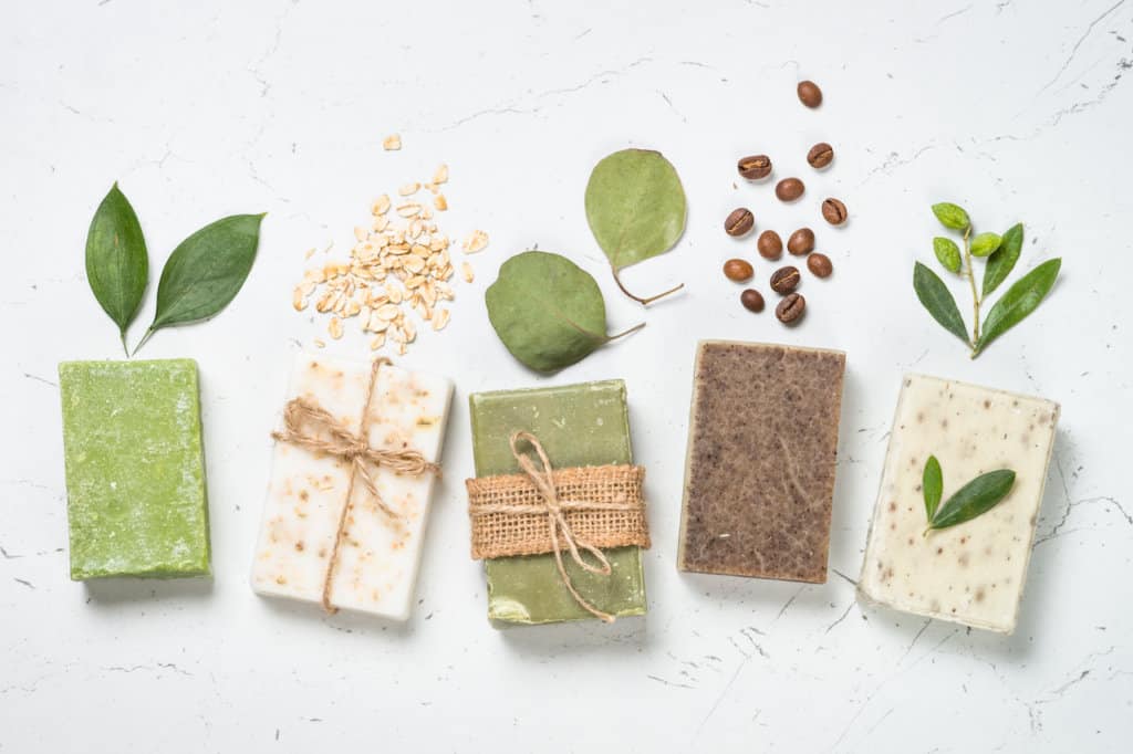 Natural soap bars with ingredients on white background. Tea tree oil, oat flackes, eucalyptus, olive, coffee soap.