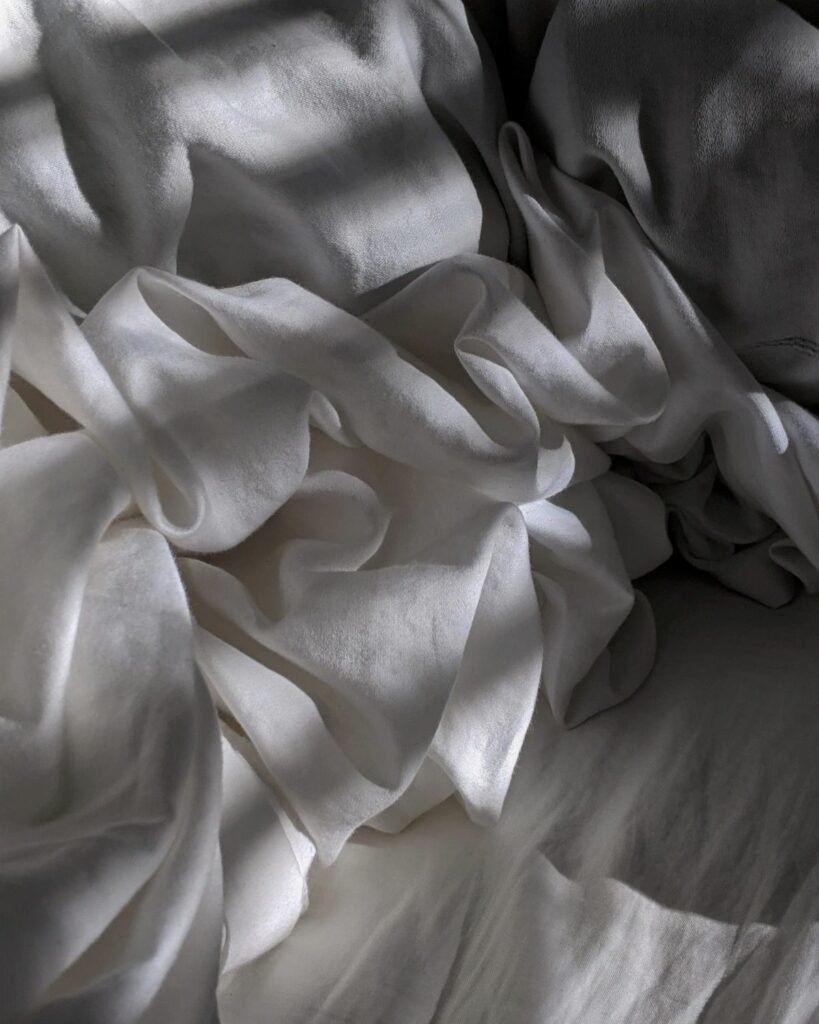 Image of a crisp, white bedding set including a fluffy comforter and soft pillows, creating an image of pure, clean comfort and suggesting a serene and peaceful sleep space.