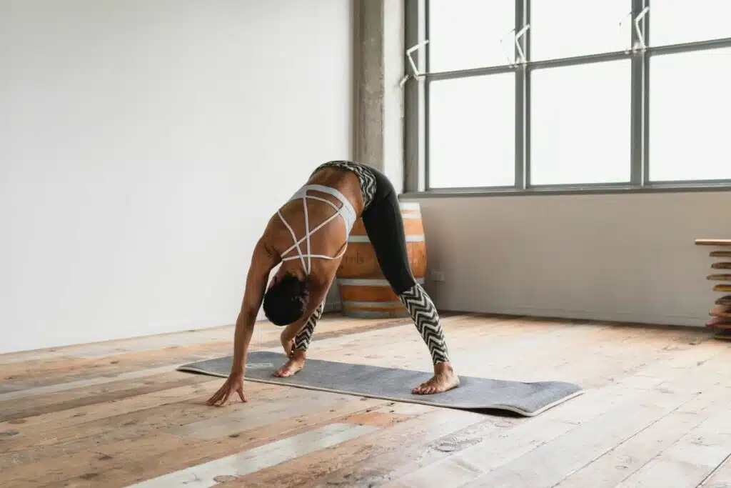 Image of a woman in mid-yoga pose, demonstrating strength and flexibility on a yoga mat in a serene environment, embodying a sense of calm and mindfulness.