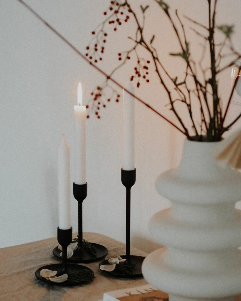 Image featuring three lit candles of varying heights, their flames casting a warm, inviting glow that creates a peaceful and serene atmosphere.
