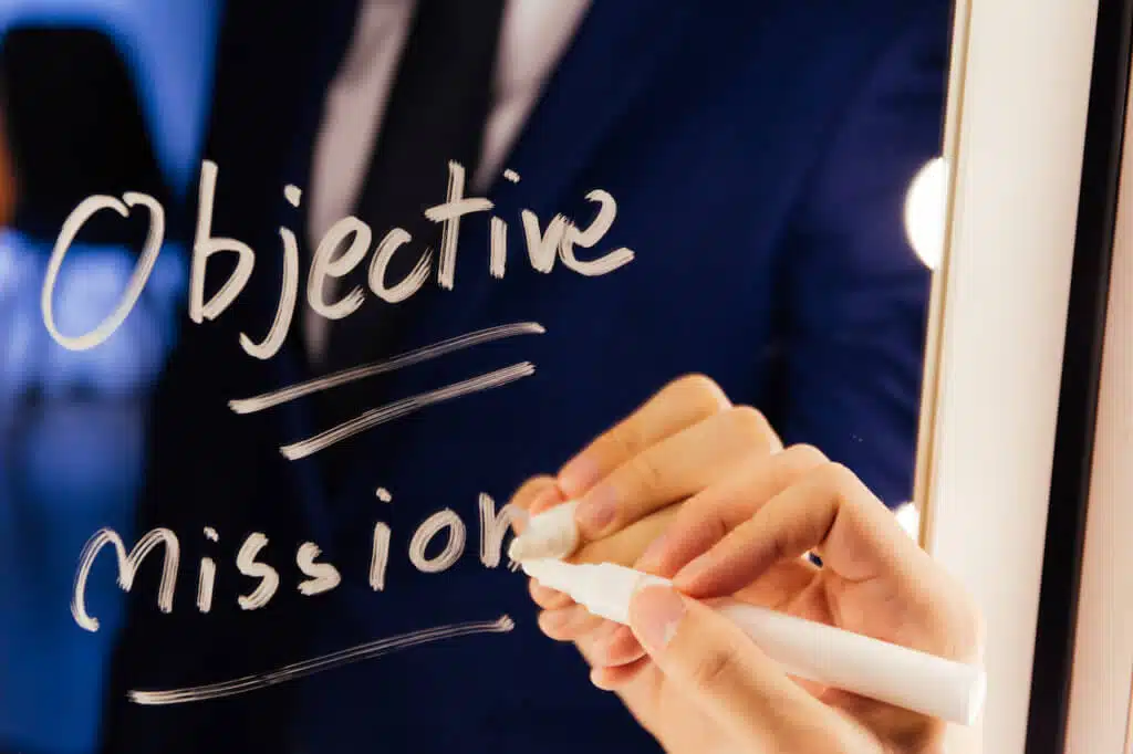 Smart business man writing the word Objective Mission on the mirror board - Objective Mission business text letter