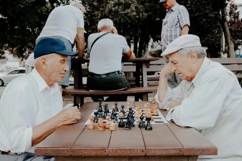 Two elderly men deeply engrossed in a game of chess, strategizing their next moves.