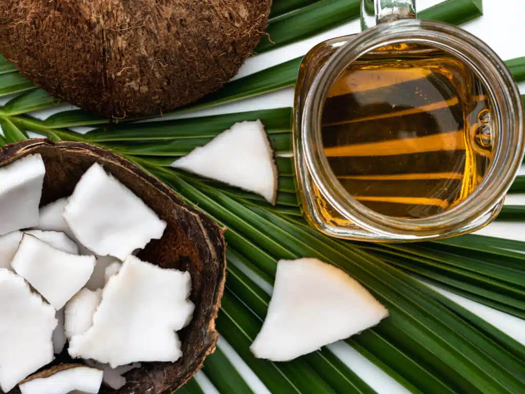 Coconut meat and coconut oil in glass bottle on coconut leaf.