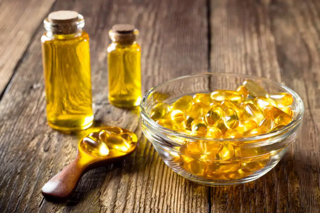 Fish oil capsules on wooden background, vitamin D supplement