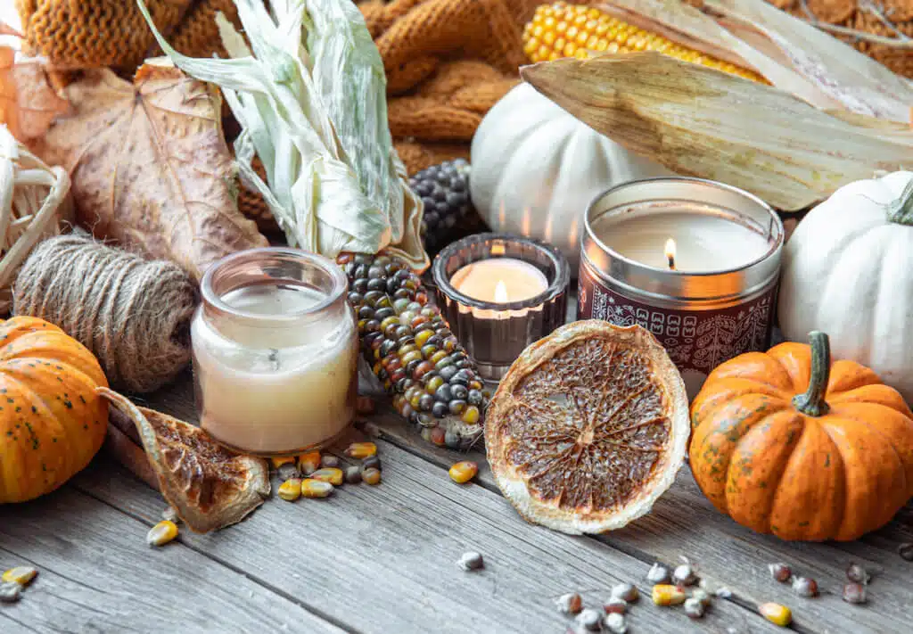 Cozy composition with candles, pumpkins, corn on a wooden surface in a rustic style.