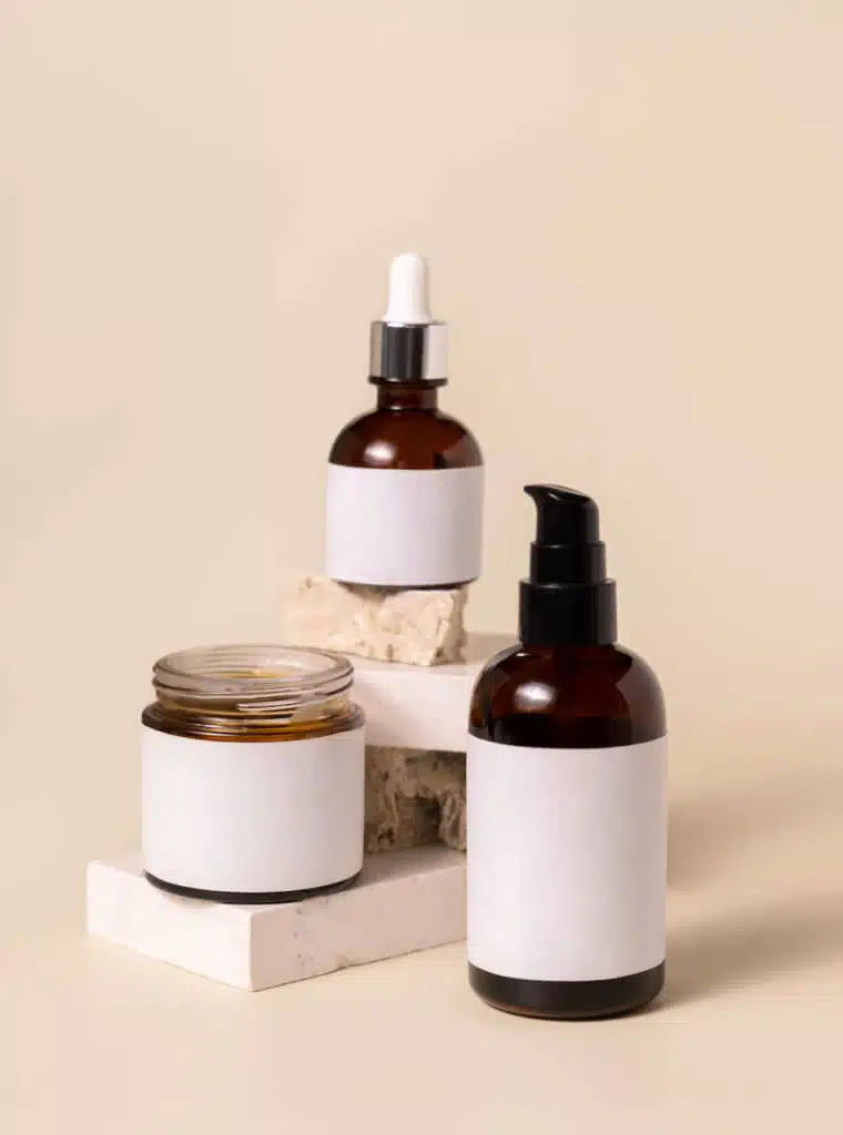 Cosmetic bottles on beige stones on light beige close up. Labels Mockup. Skincare beauty product packages. Natural cosmetics, minimal boho composition