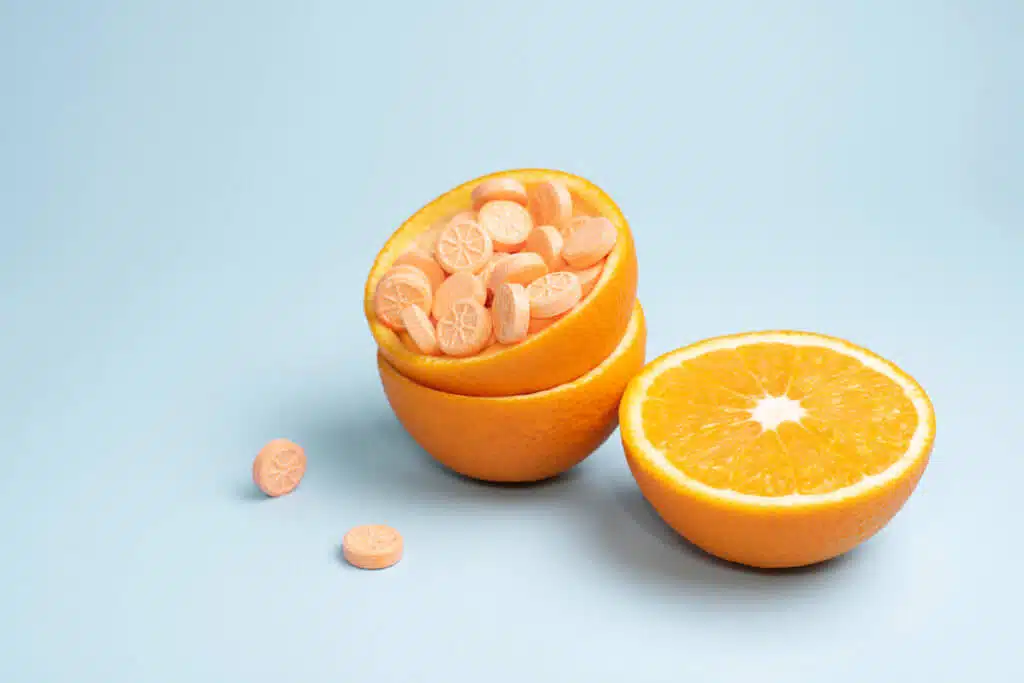 vitamins, Half orange and peel with vitamin C tablets on a blue background, close up. Vitamin C pills as an alternative to citrus fruits. Immune booster concept.
