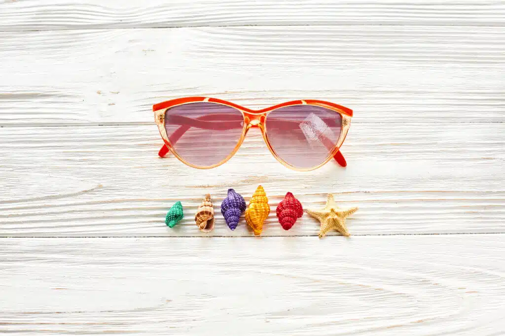 summer travel vacation concept, space for text, flat lay. sunglasses and colorful shells starfish on white wooden background top view. hello summer holiday. wanderlust.