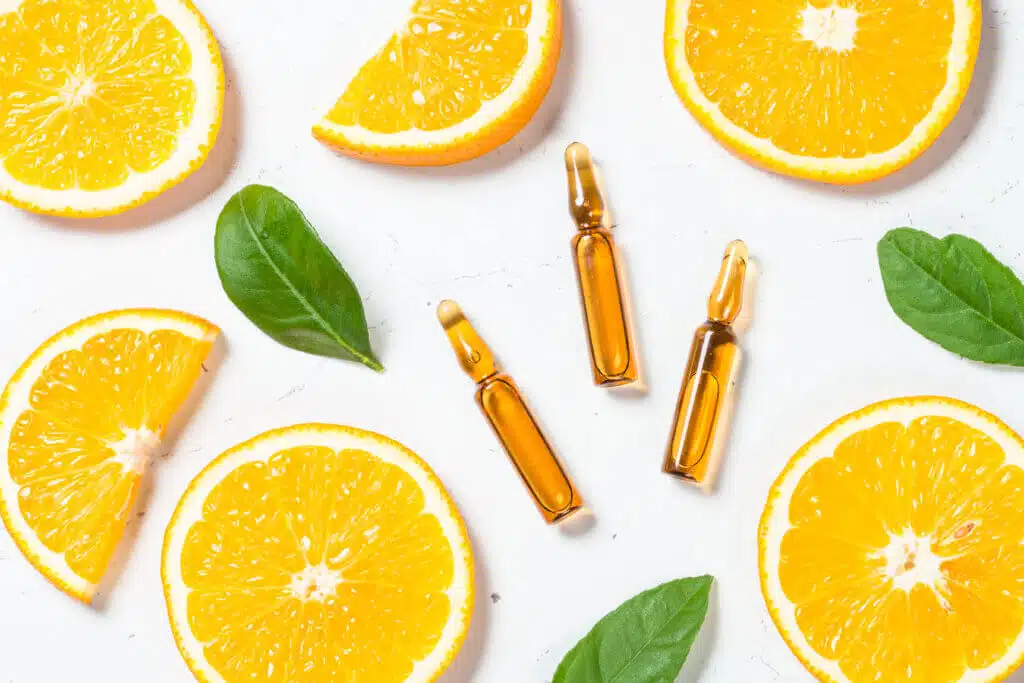 Vitamin C ampoules. Fresh citrus fruits and glass ampules. Medicine, healthcare concept. Top view at white background.