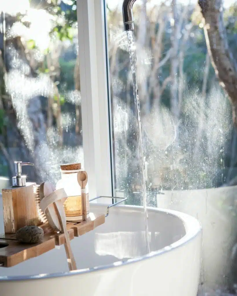 A white bathtub surrounded by various beauty products, including bottles of shampoo, conditioner, and bubble bath, creating a relaxing self-care atmosphere.