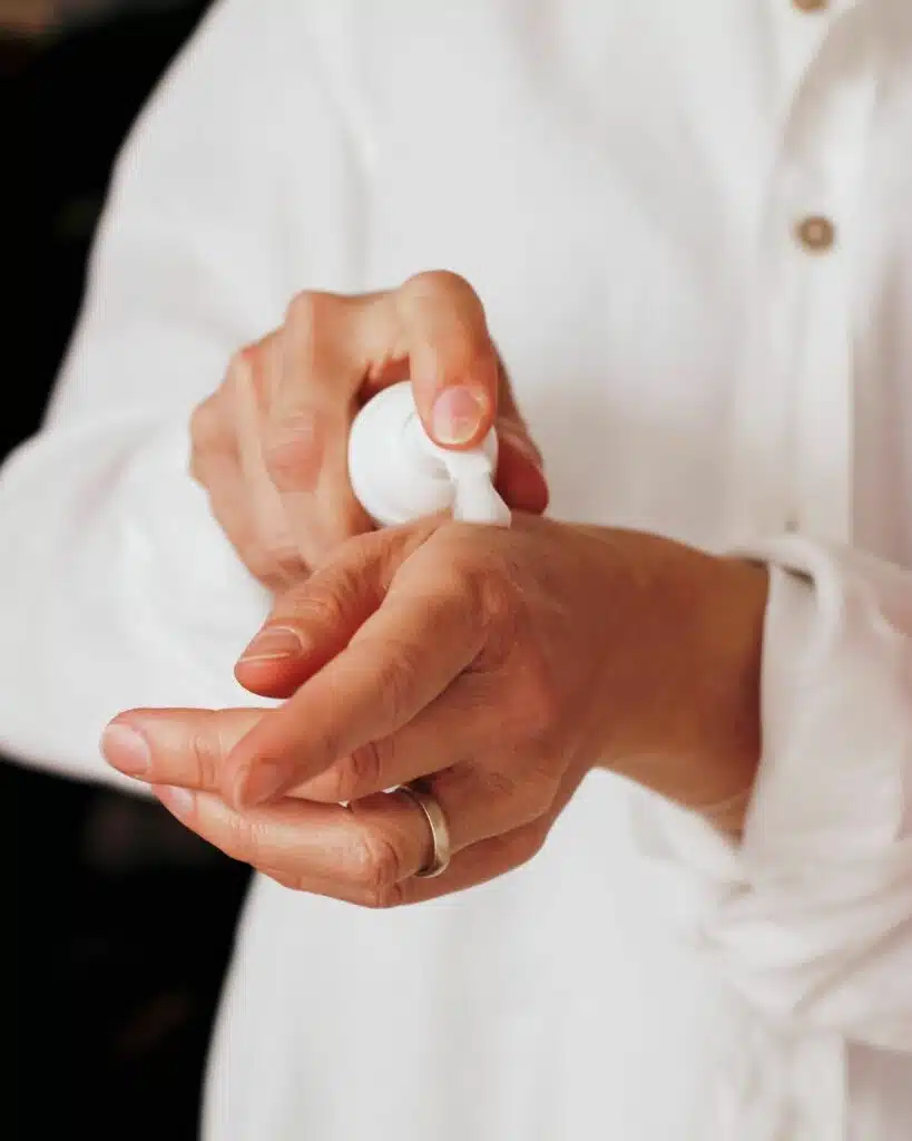 A woman massaging a dollop of hand cream into her skin, demonstrating a part of her personal care routine.