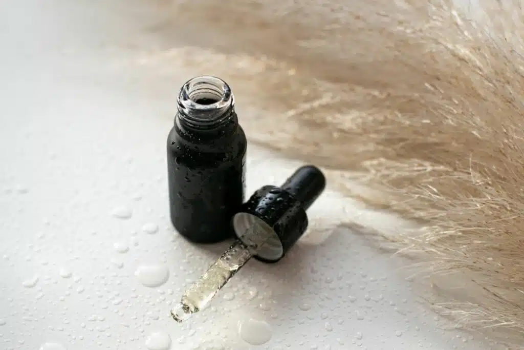 Glass bottle filled with golden face oil, topped with a dropper, standing on a neutral background.