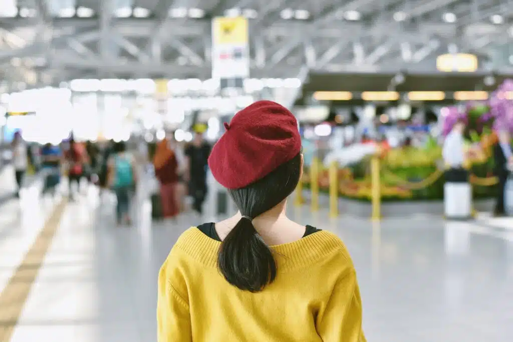 Asian woman standing in trade fair exhibition hall, Blurred background of large crowded people at big event with copyspace for product sourcing 