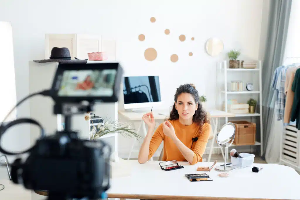 Young adult woman sitting alone in her room shooting new video for her beauty blog channel about clean beauty and clean ingredients 