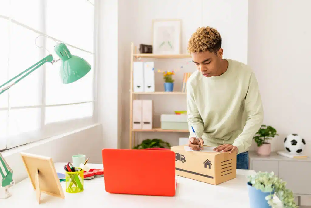 Hispanic latin young seller man preparing second hand packaging before sending to buyer - Young male seller writing address on box