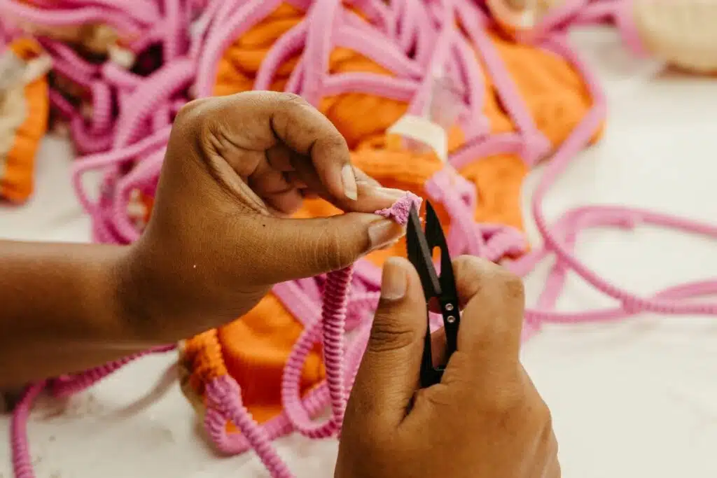 Woman meticulously designing and crafting a piece of swimwear on a worktable, surrounded by fabric and sewing tools.