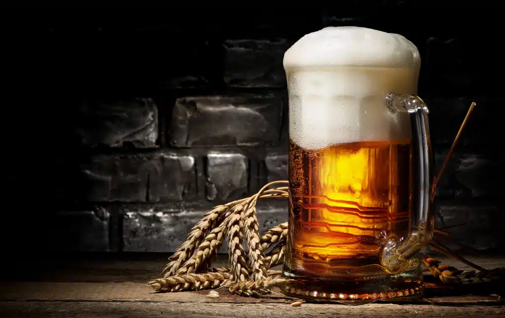 Beer in mug and wheet on wooden table and black background