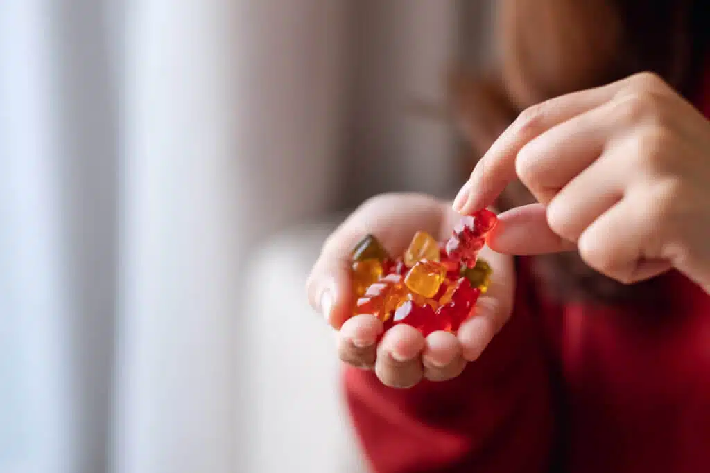 Closeup image of a woman holding and picking a jelly gummy bear