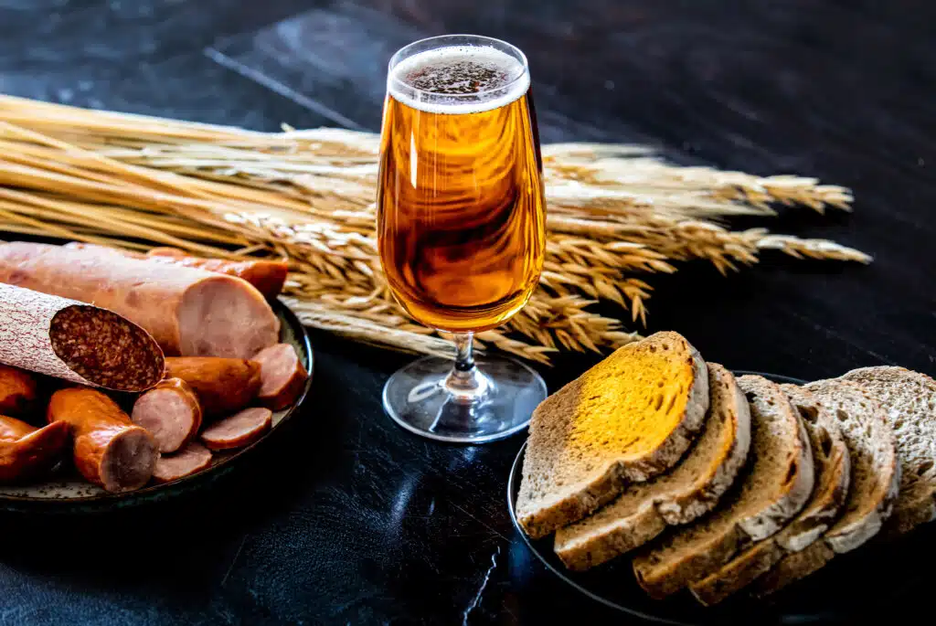 glass of beer, sausages and bread on the table