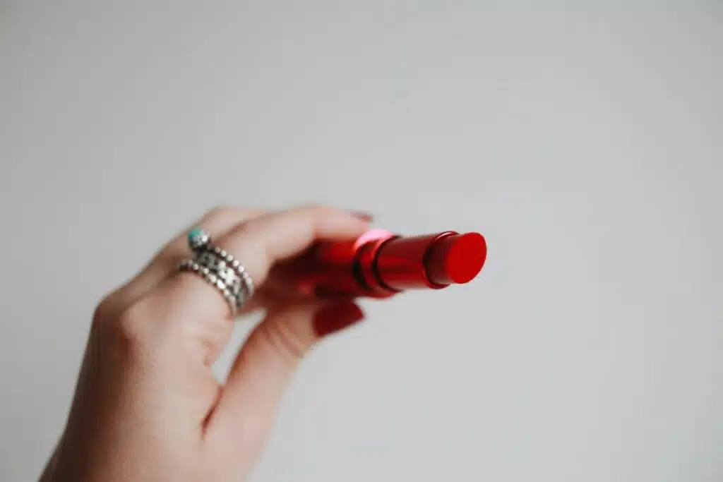Image of a single tube of lipstick, elegantly designed with its cap off, revealing the vibrant shade of the product, placed against a simple background.