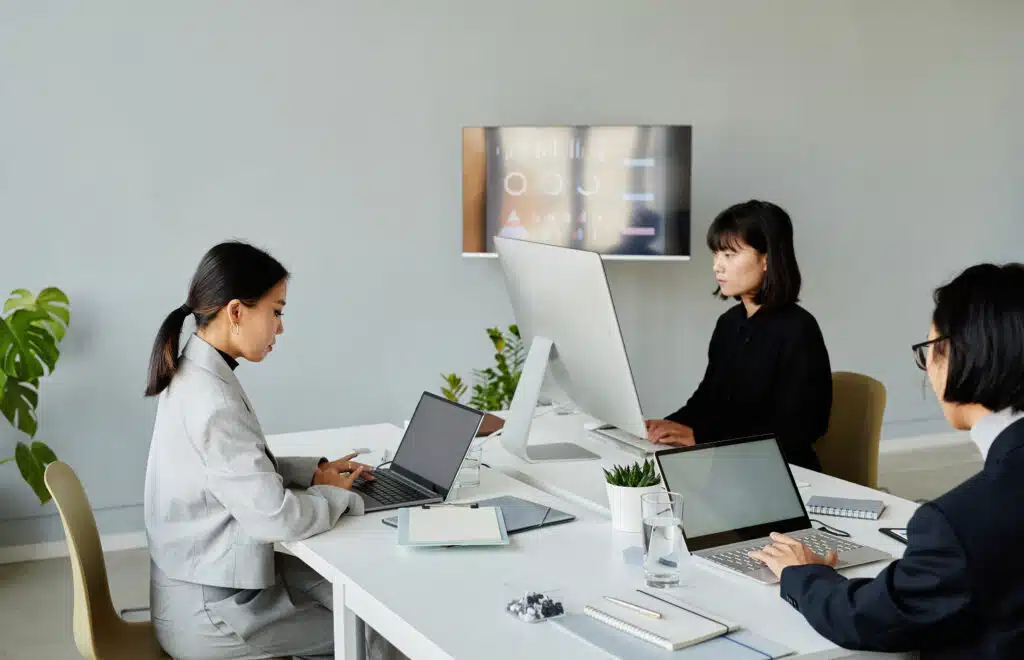 Minimal shot of group of Asian business people working with computers in modern white office
