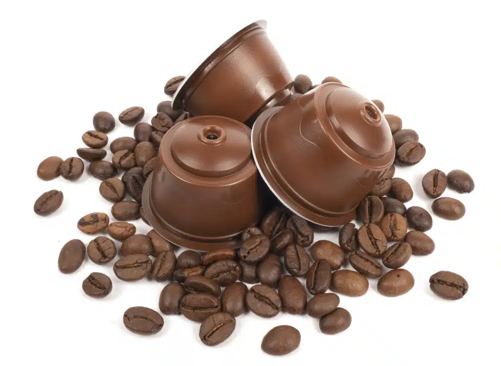 Espresso coffee capsules and coffee beans on white