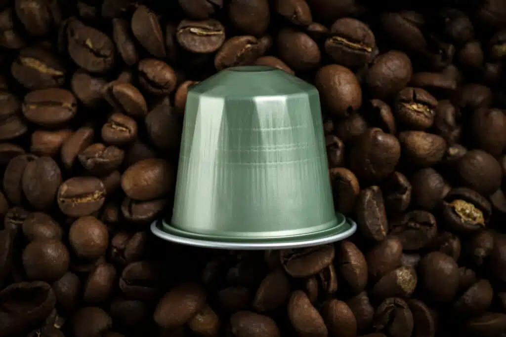 A grey coffee capsule for a machine placed on the coffee beans