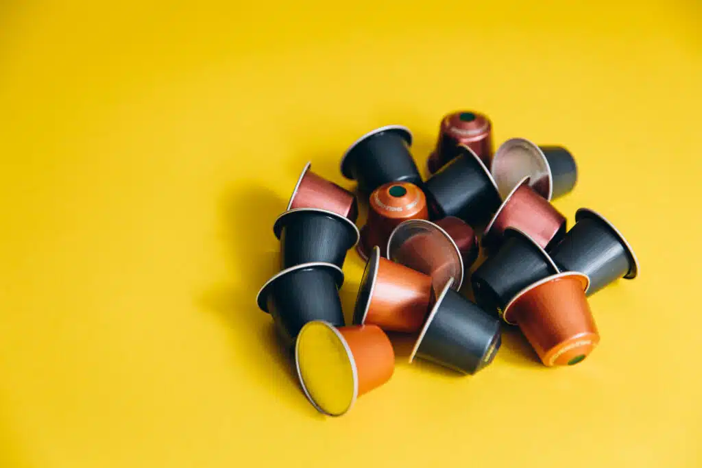 Set of colorful capsules for making instant coffee at home. Disposable pods on yellow background. Hot morning beverage.