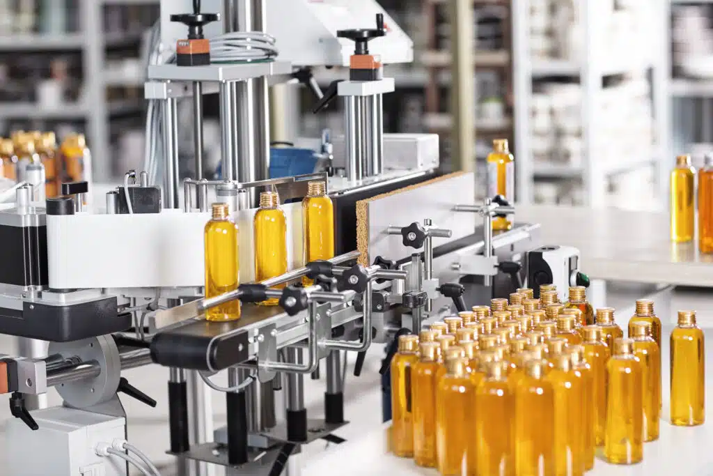 Cosmetics factory. Bottling line filled with yellow shampoo. Automated process on factory. Line of bottles filled with yellow substance going on conveyor to be twisted. Research, innovation, creation