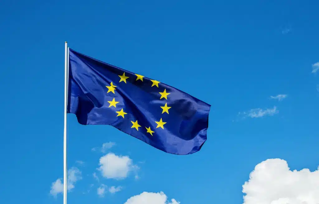 European Union EU flag waving in the wind over cloudy blue sky low angle view close up.