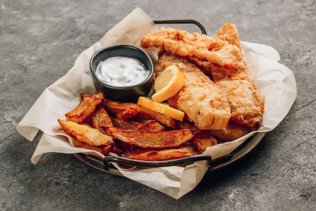 Traditional British Fish and Chips with tartar sauce on concrete background.