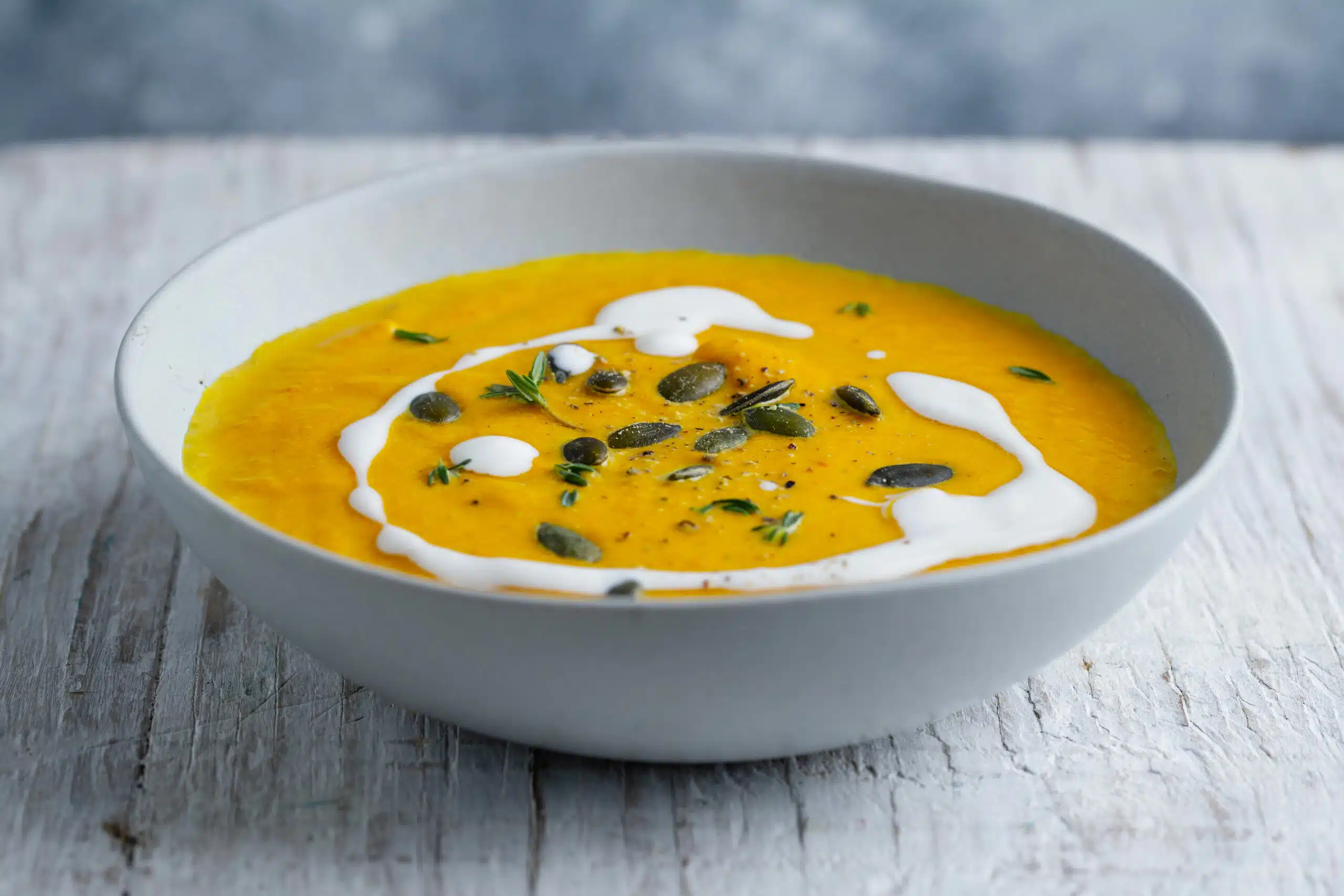 Pumpkin soup with cream and seeds served in bowl. Closeup