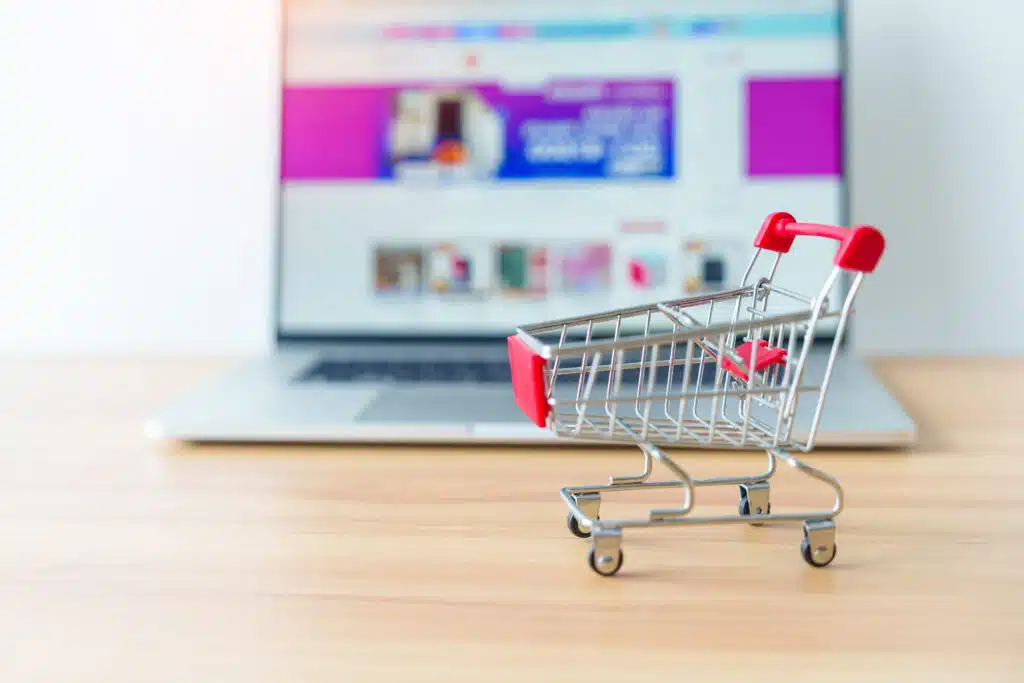 Shopping cart and laptop computer with marketplace website. business, technology, ecommerce, digital banking and online payment concept