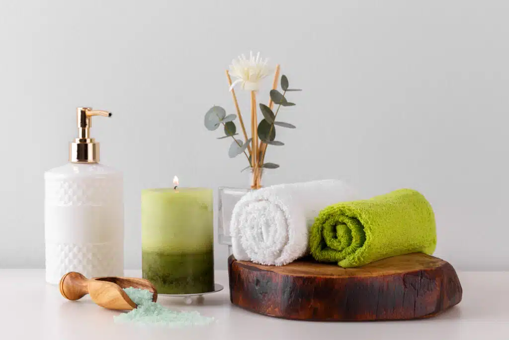 Health care and spa items on white shelf, green towels candle soap and salt