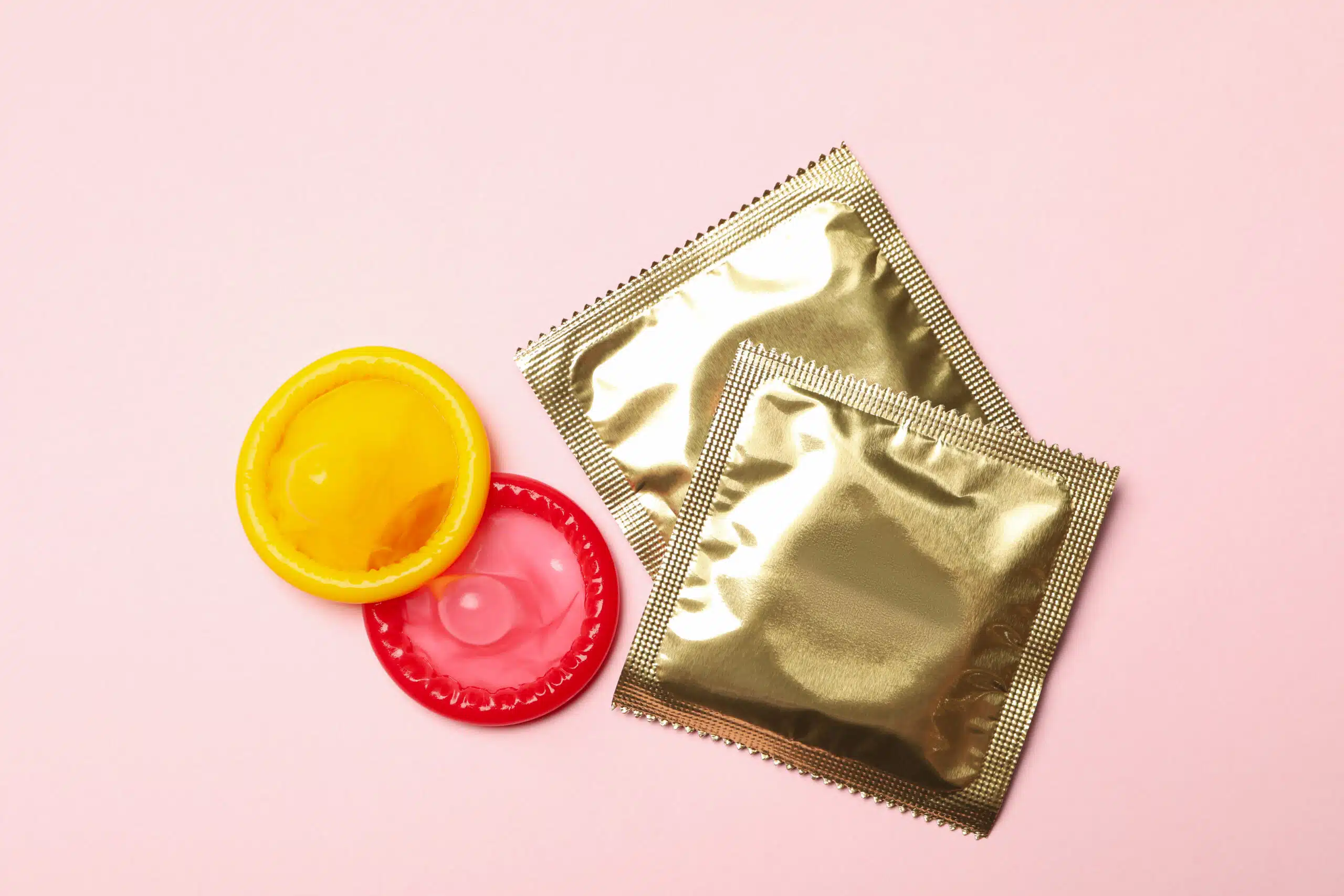 Yellow and red condoms on pink background