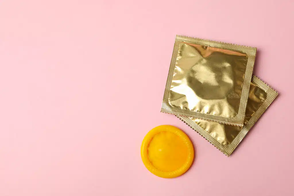 Yellow condom and blank condoms on pink background