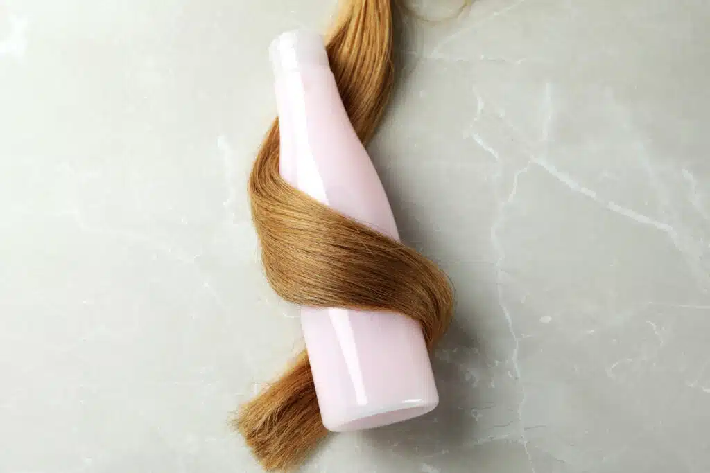 A lock of female hair with shampoo bottle