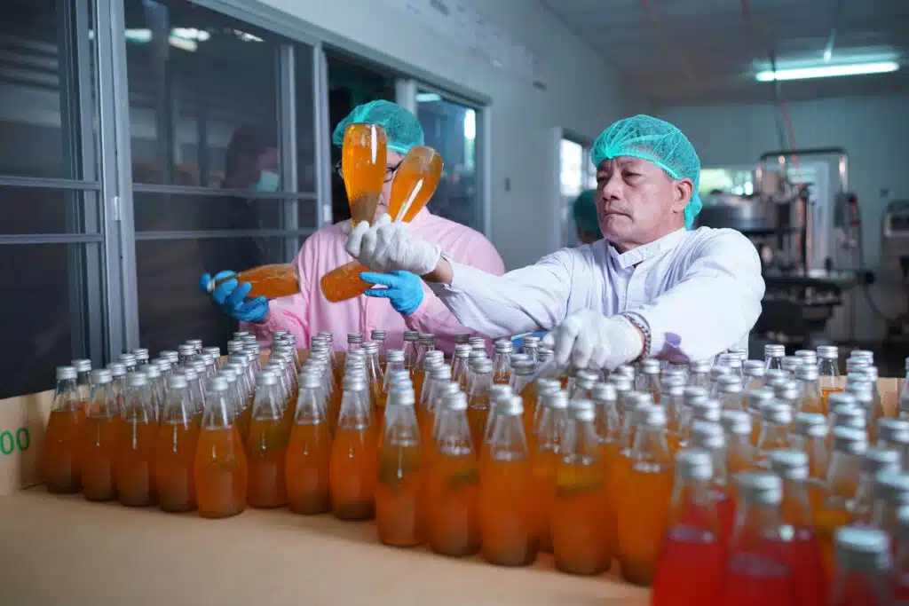 worker controlling the work of machine in production line at beverage industry.