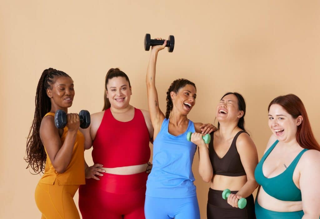 A photo of women confidently showcasing fitness apparel and using equipment from a private label fitness brand, set against a naturak background.