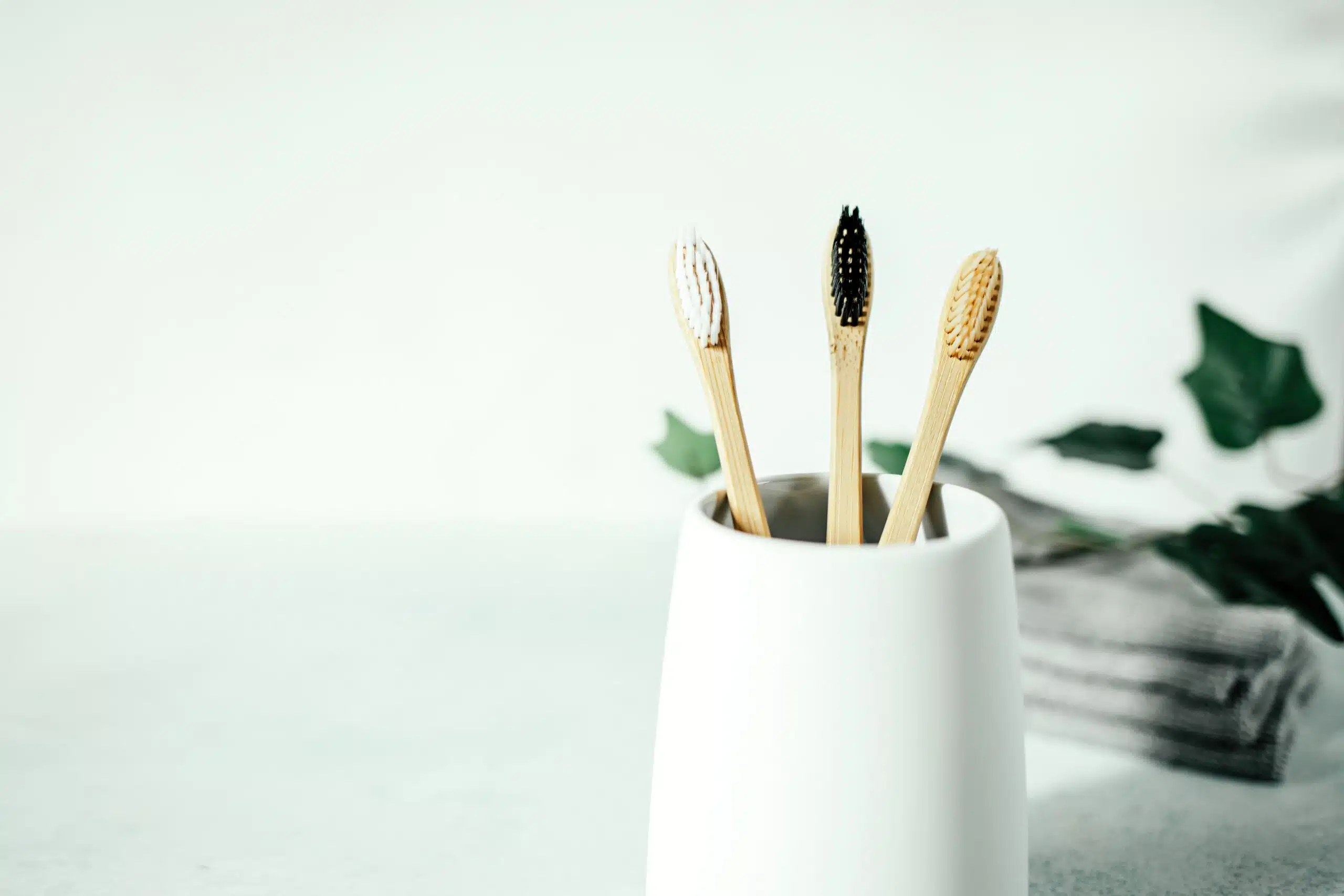 Three bamboo toothbrushes in a cup and grey towels
