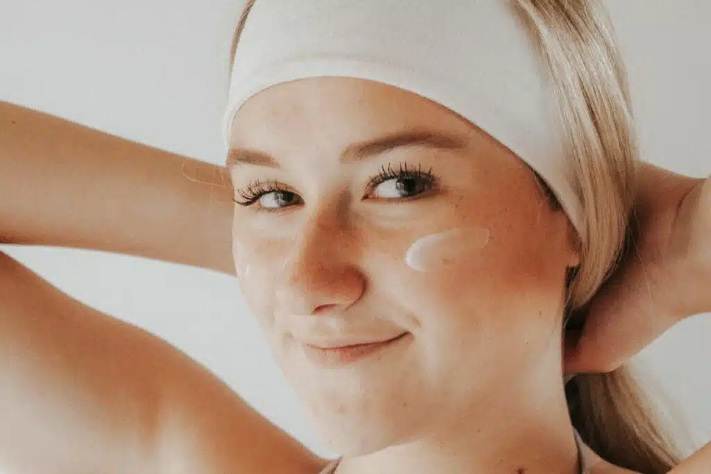 Woman applying skincare products to her face, reflecting a daily beauty routine.