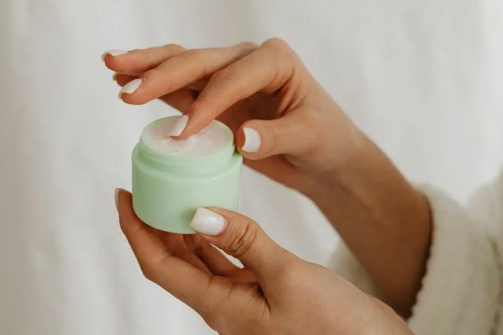 Close-up of a woman gently applying a dollop of face cream on her wrist, evaluating its texture and consistency.