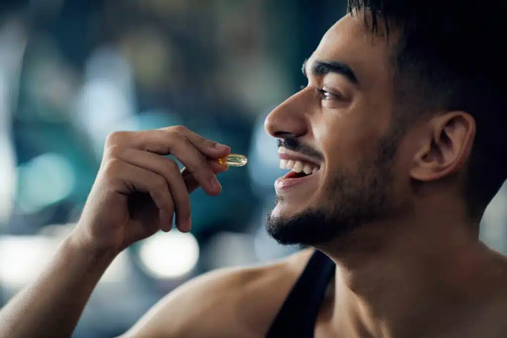 A man taking a supplement pill, demonstrating a commitment to maintaining his health and wellness.