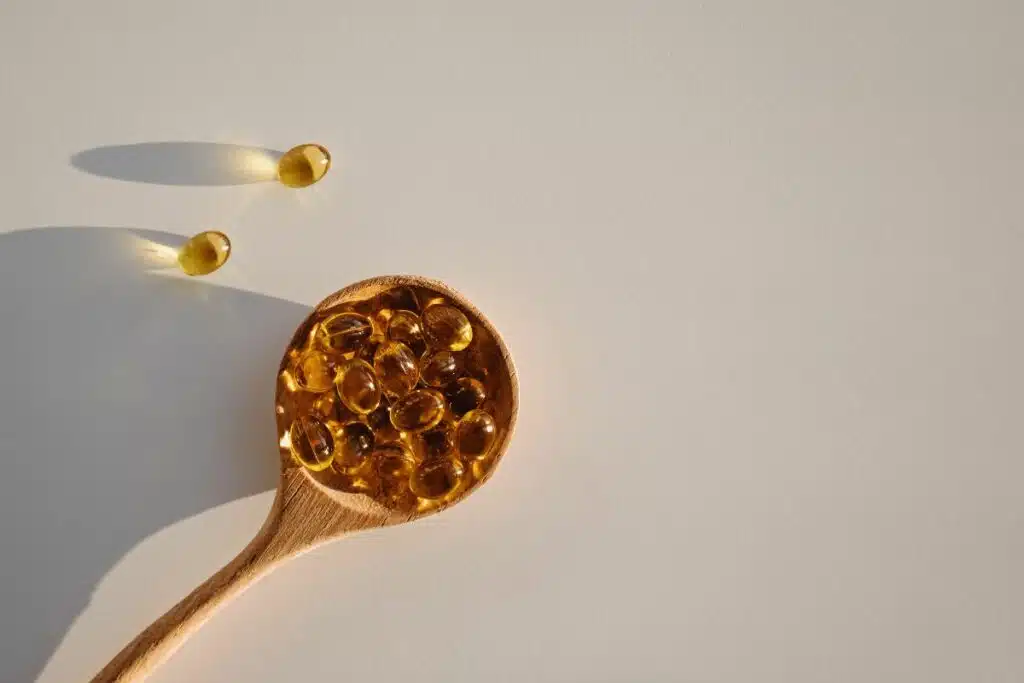 A spoon holding a dose of Vitamin D supplement, placed under the sunlight, which is a natural source of Vitamin D, highlighting the importance of sun exposure and supplementation for maintaining optimal health.