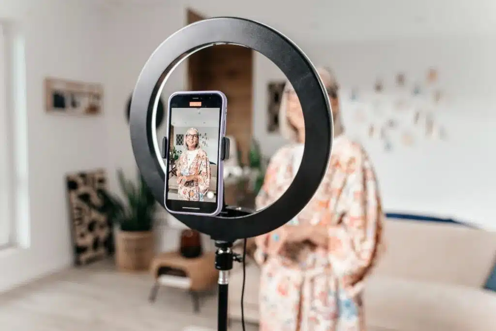 Influencer positioned inside a lit ring light, with a smartphone placed in front, ready for content creation.