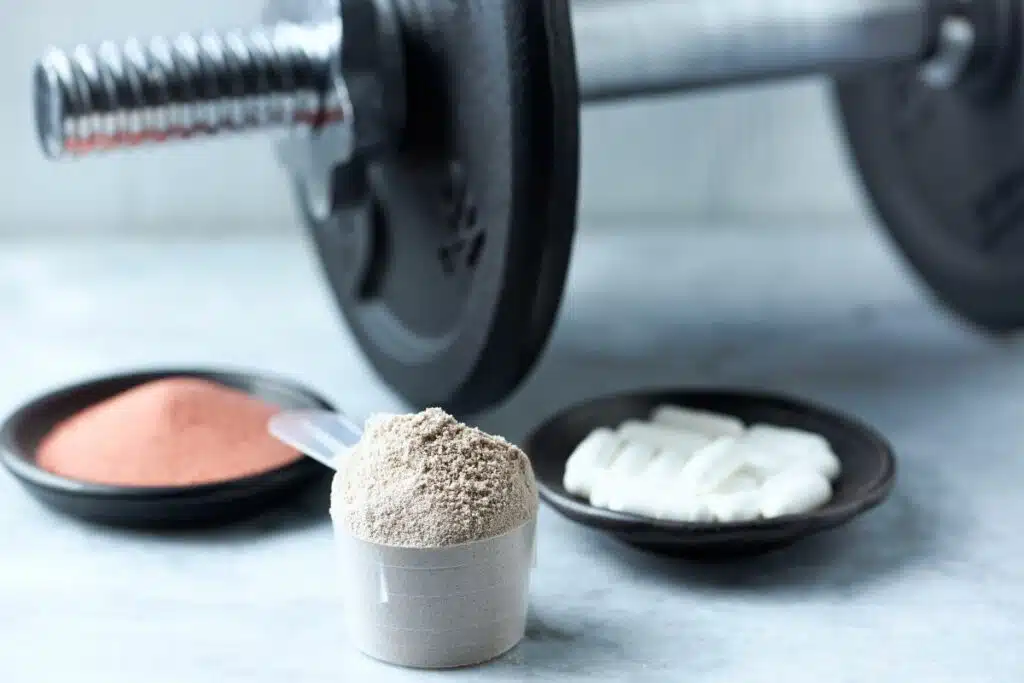 A container of creatine powder with a scoop, commonly used by athletes and fitness enthusiasts to improve muscle strength and exercise performance.
