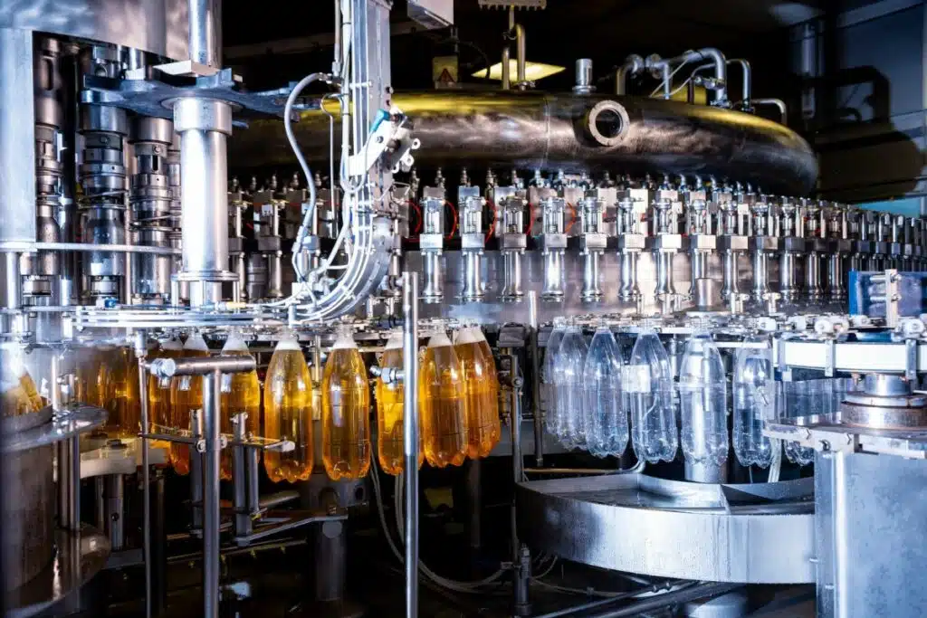Bottles being filled with apple juice on a production line.