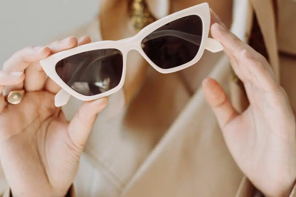 Image of a woman holding a pair of stylish sunglasses.